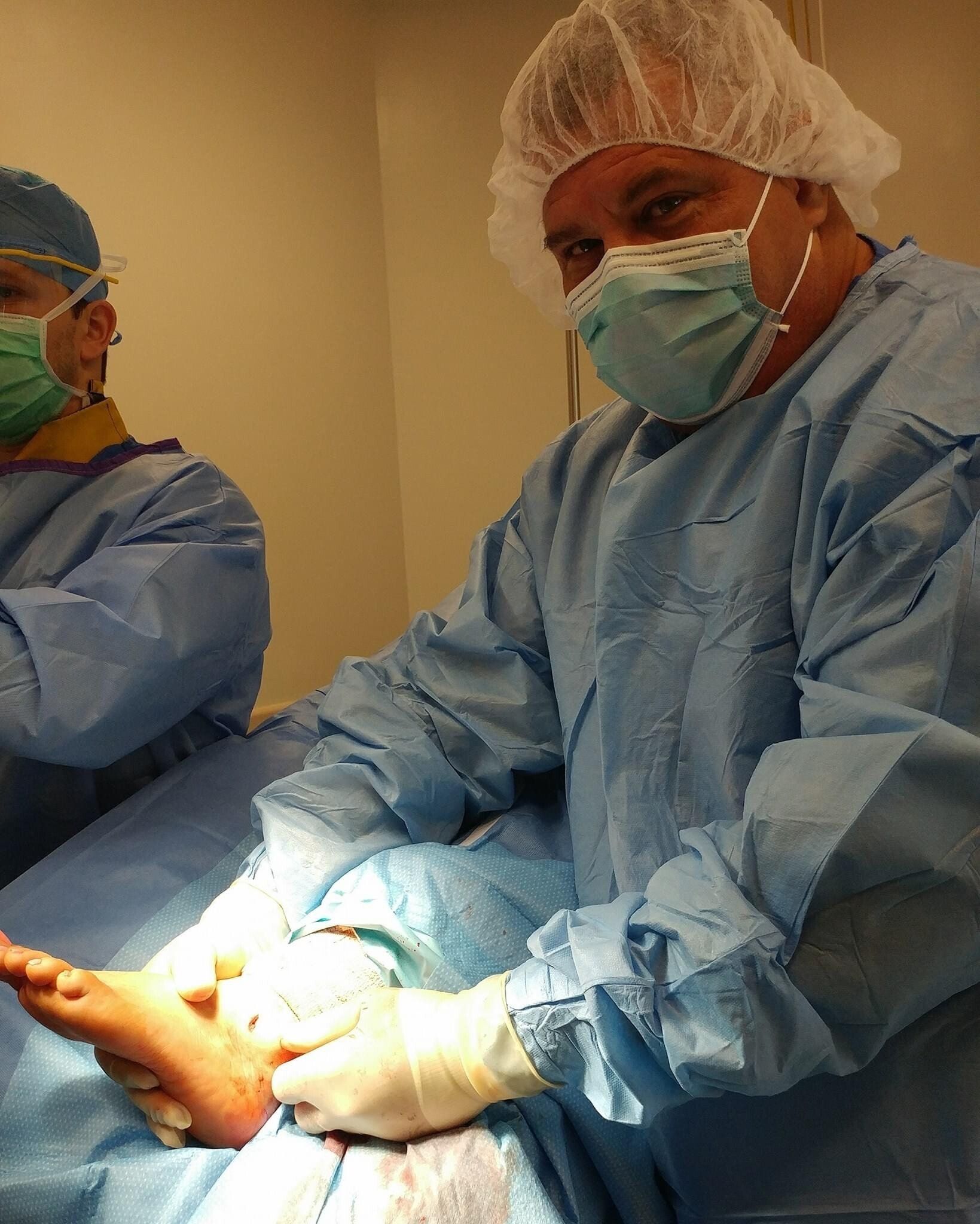 A surgeon wearing a mask and gown is operating on a patient