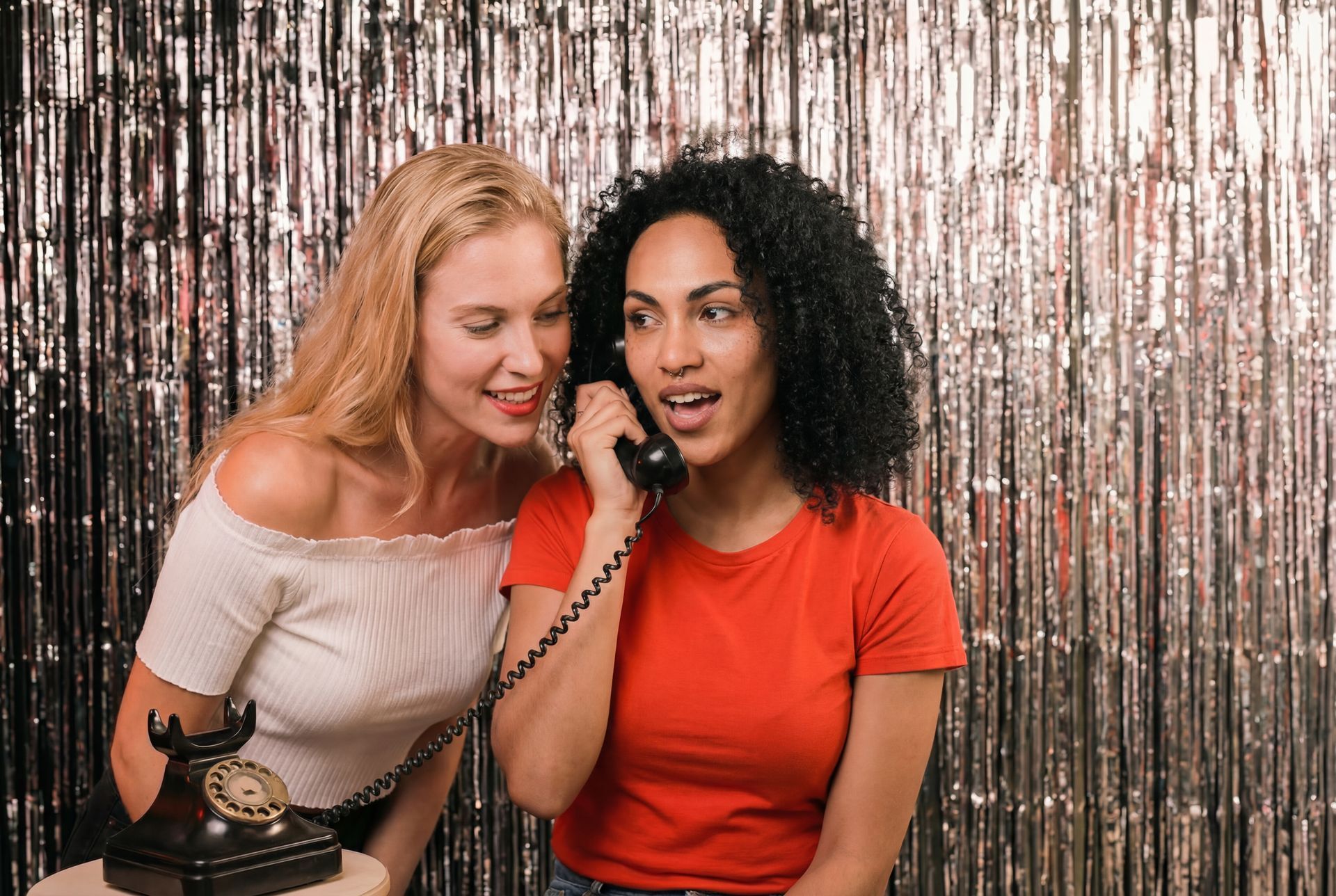 Three friends posing for a photo. One holds heart-shaped glasses. All are smiling and gathered closely.