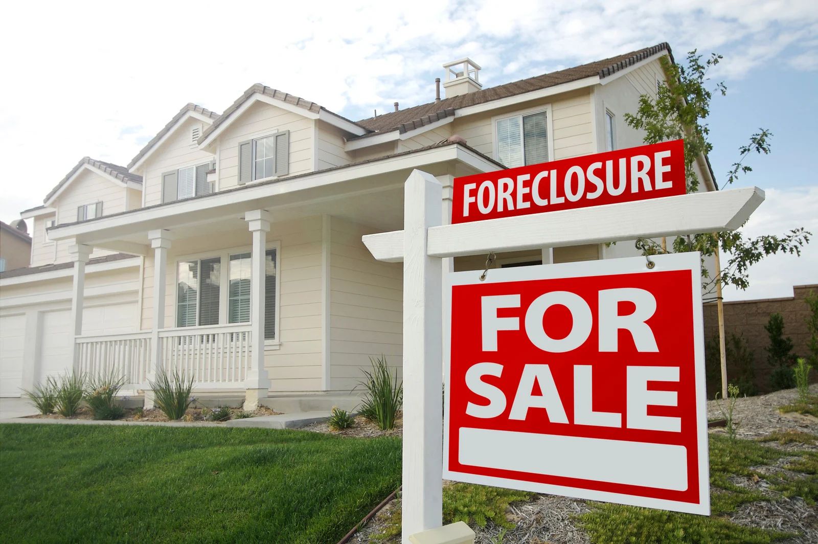 White house for sale, foreclosure sign in front.