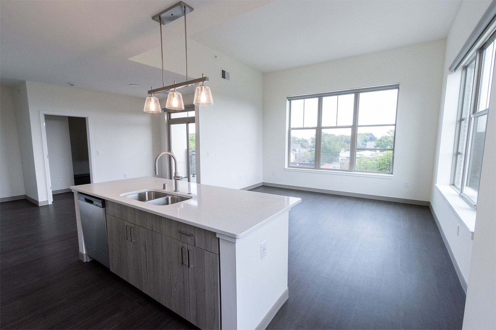 Modern kitchen with island, stainless steel appliances, and large windows.