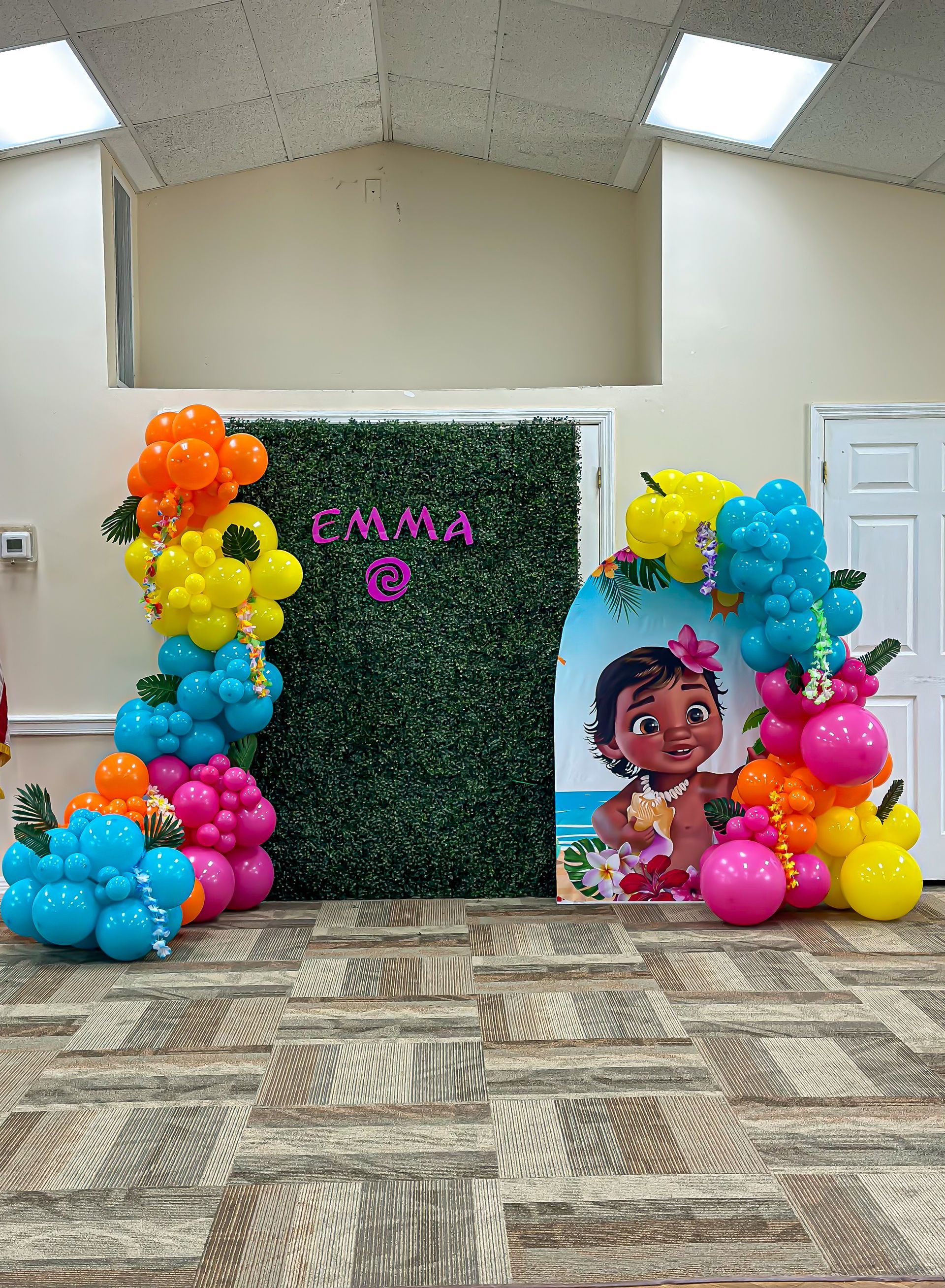 A room filled with balloons and a picture of a baby moana.