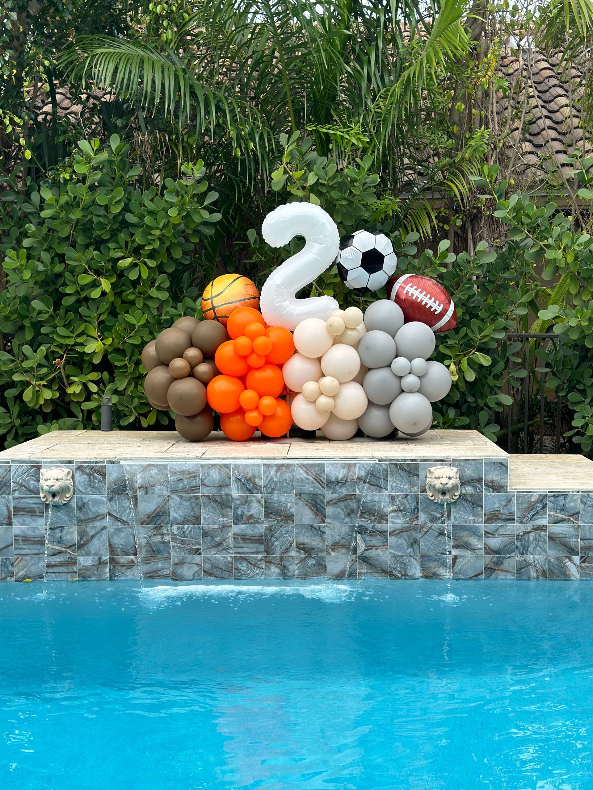 A bunch of balloons are sitting next to a pool.