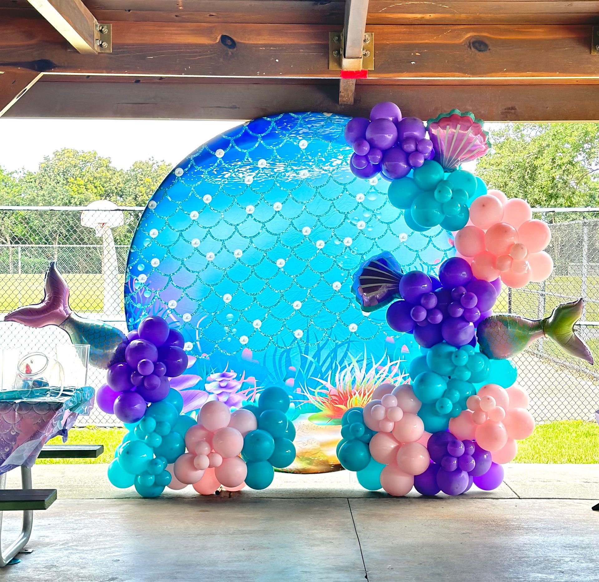 A bunch of balloons are lined up in front of a mermaid backdrop