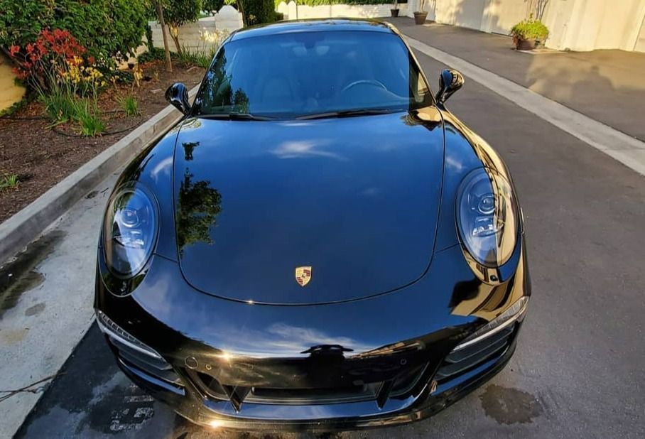 Black Porsche sports car parked on a driveway, front view.