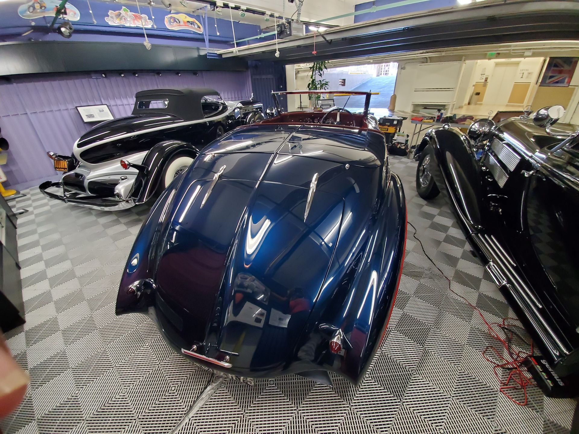 Blue classic car with others in a garage.