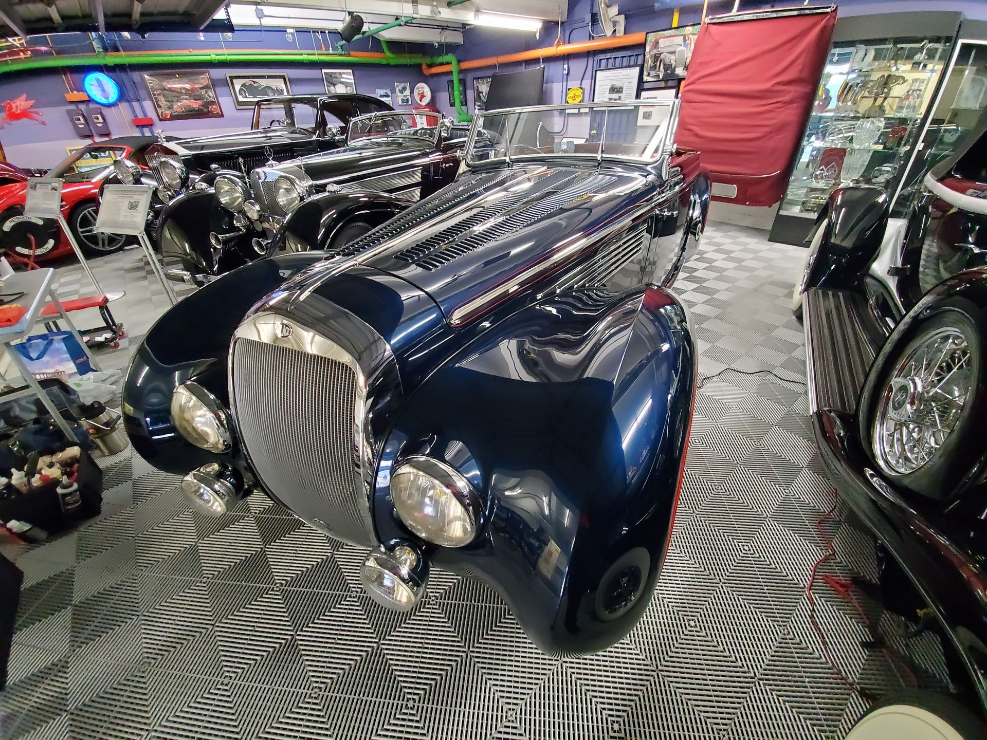 Blue vintage Bentley convertible in a car showroom.