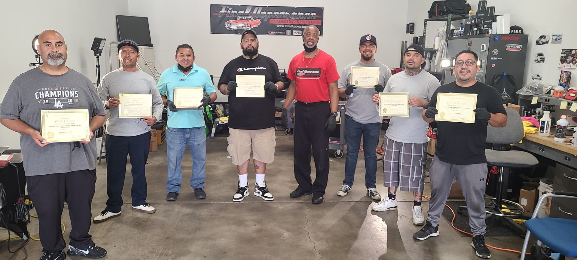A group of men holding certificates posing inside a shop.