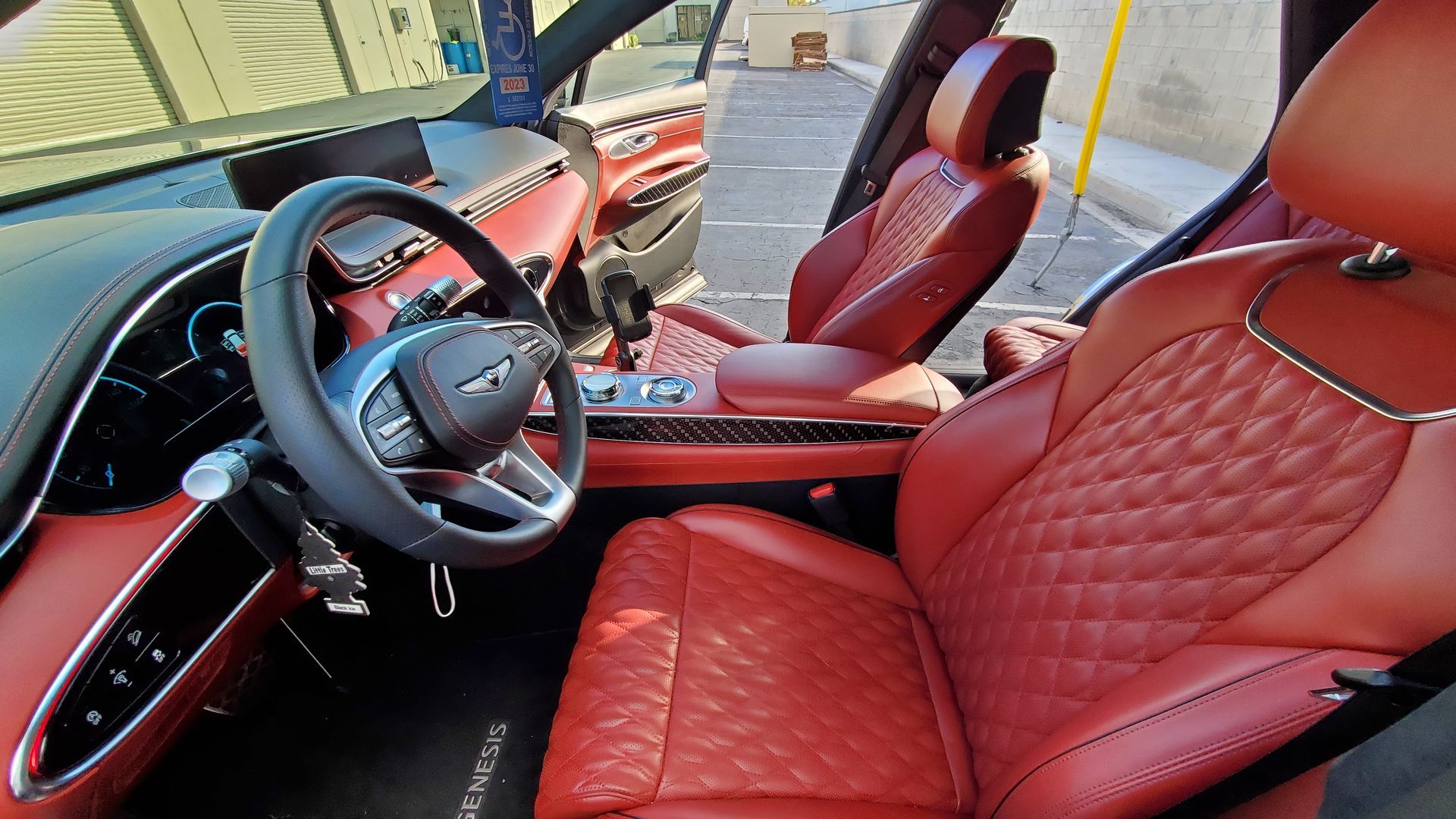 Red leather interior of a Genesis SUV with a quilted pattern on the seats. The steering wheel and dashboard are visible.