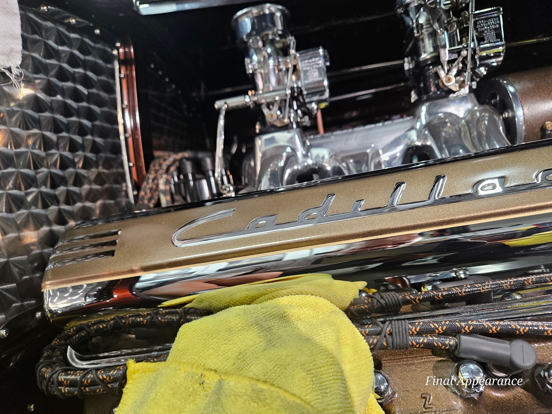 Close-up of a classic Cadillac engine. Polished metal and gold accents, cleaning rag in view.