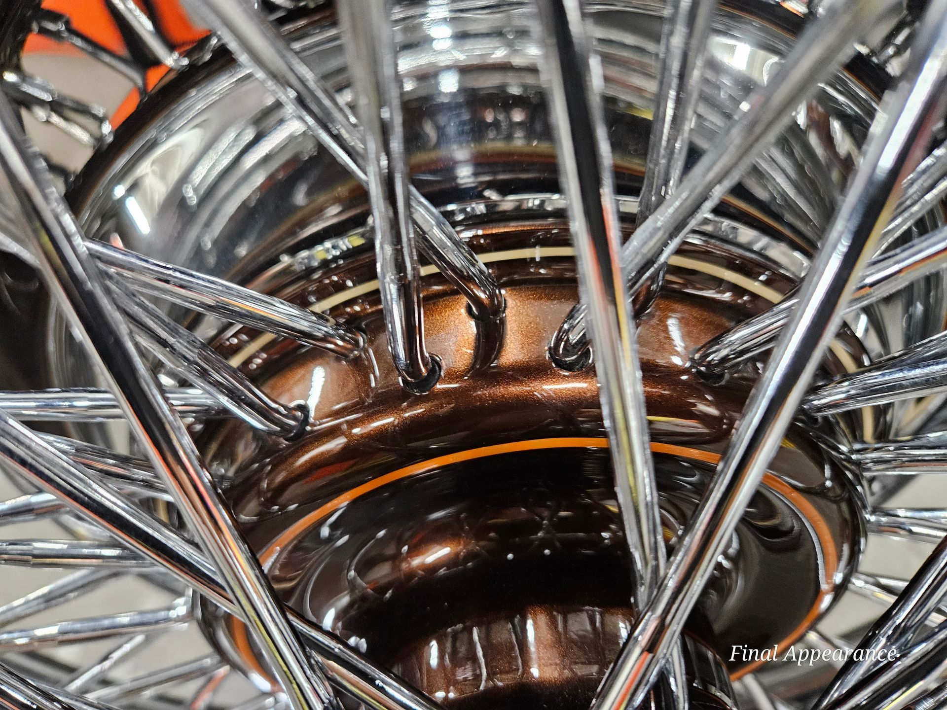 Close-up of a motorcycle wheel hub with chrome spokes, showcasing a dark copper-colored center.