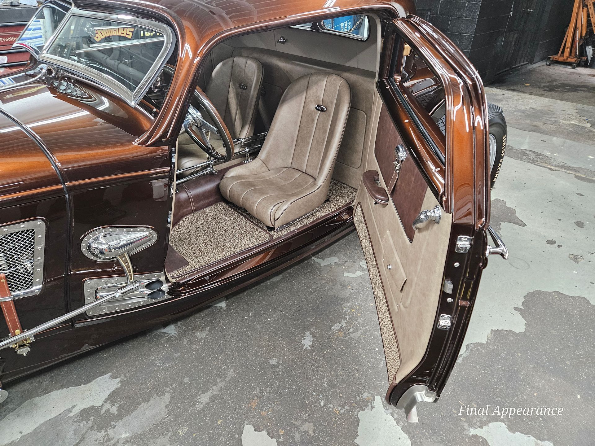 Brown customized classic car interior with open door, beige seats, and intricate detailing.