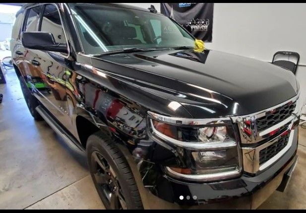 Black Chevy Tahoe SUV in a garage, shiny paint, chrome accents.