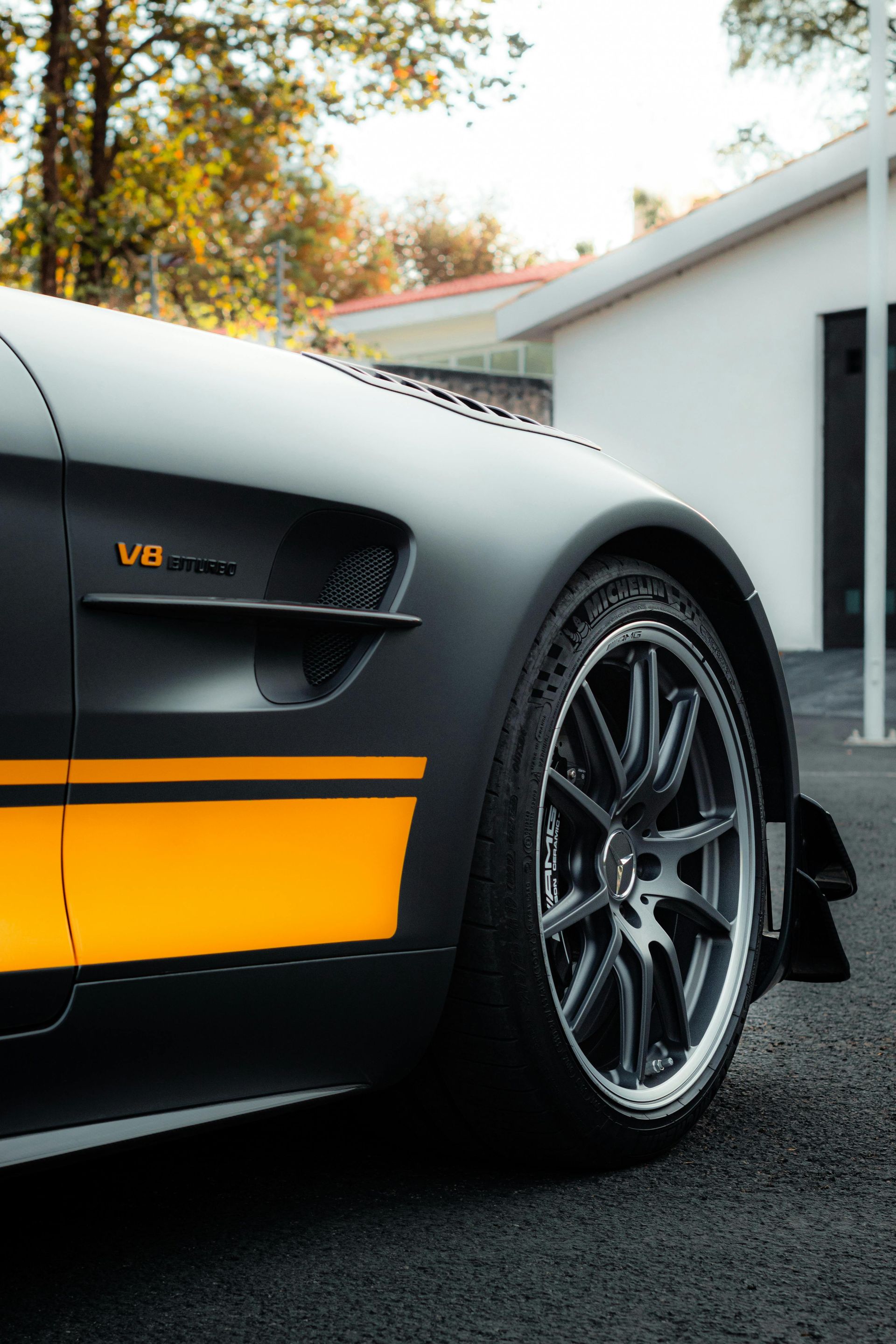Matte black Mercedes-AMG GT with yellow stripes and black rims parked outside a building.