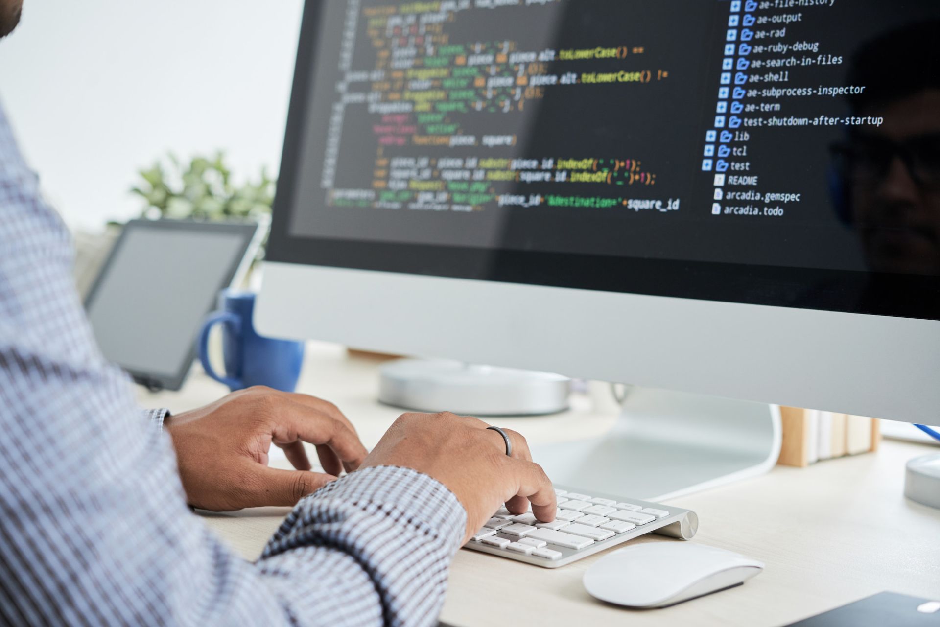 Un hombre está escribiendo en un teclado frente a un monitor de computadora.