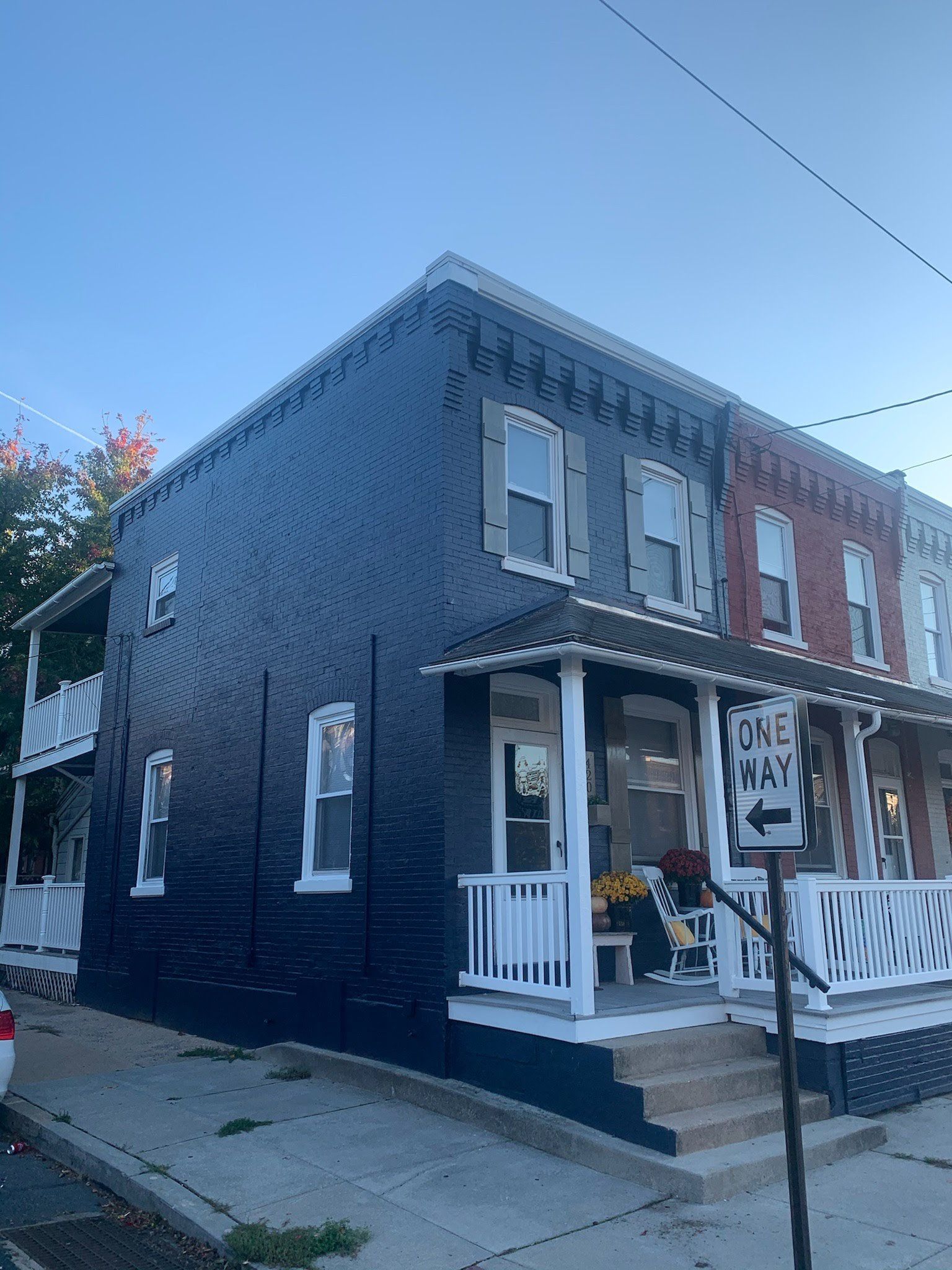 A black brick building with a white porch and a sign that says one way.