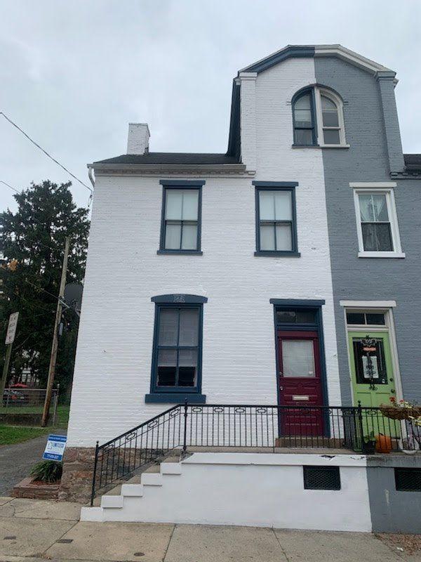 A white and gray house with a red door