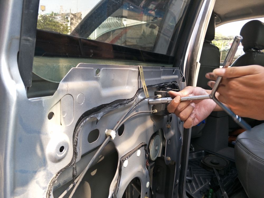 A Person is Working on a Car Door With a Wrench — Isa Auto Glass & Upholstery In Menzies, QLD