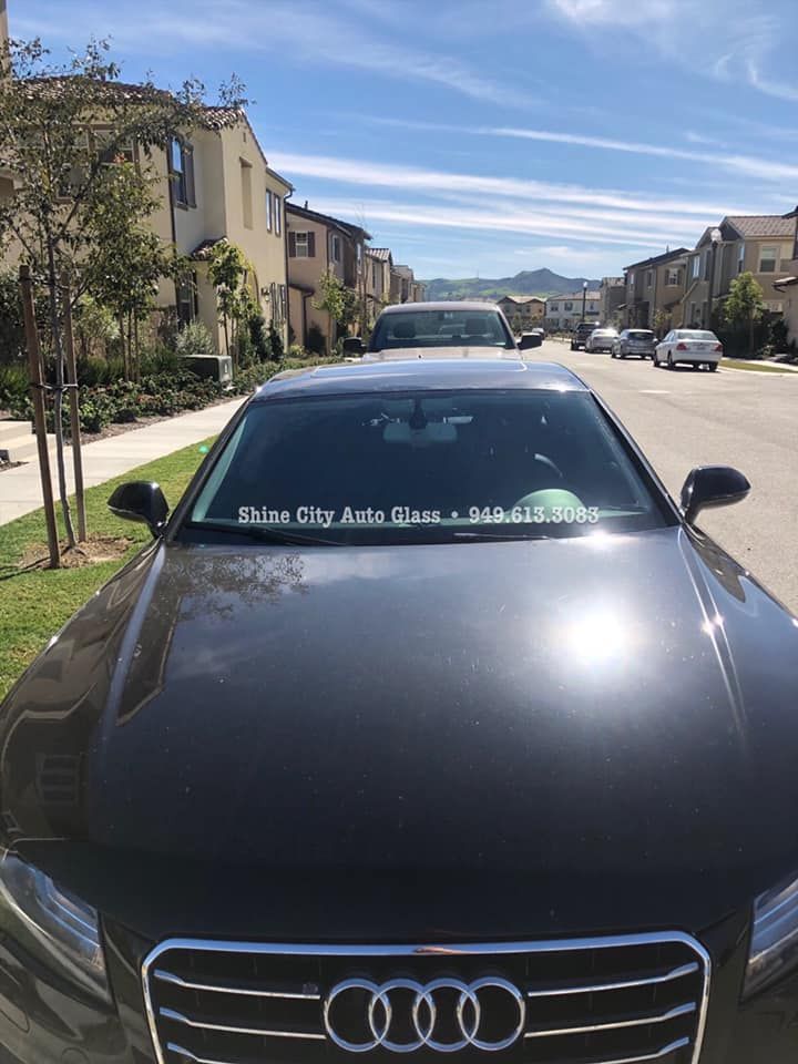 A black audi is parked on the side of the road in a residential area.