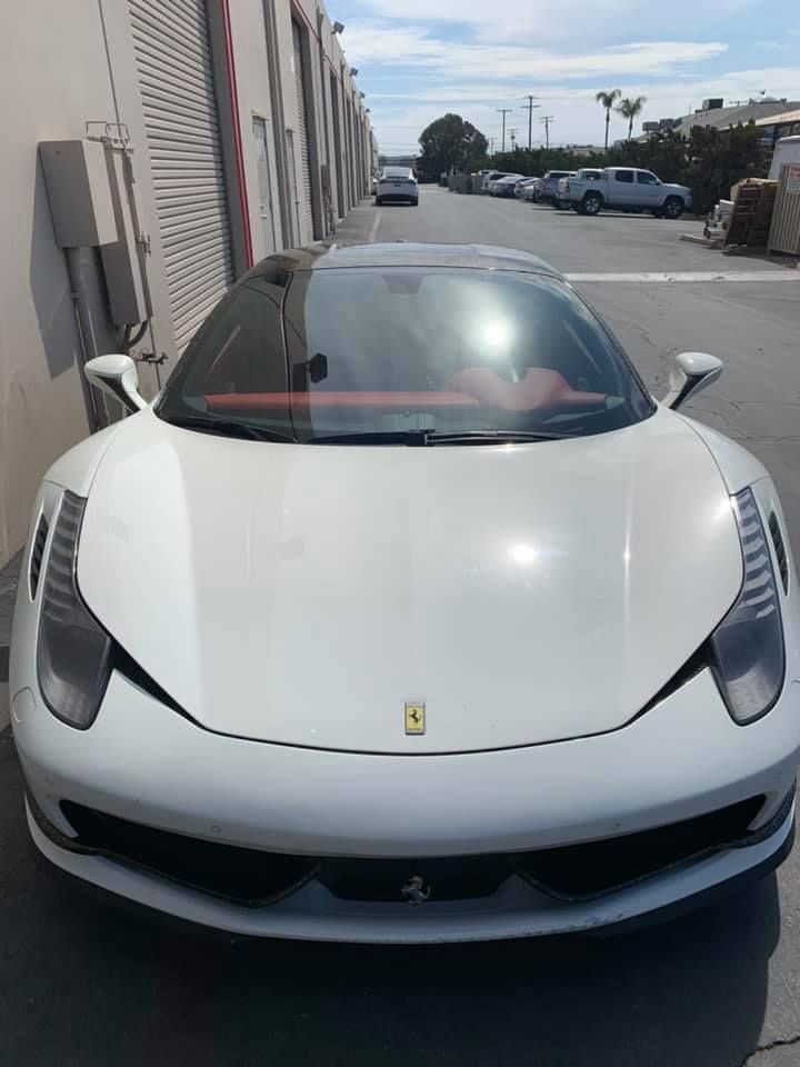 A white ferrari is parked in a parking lot.
