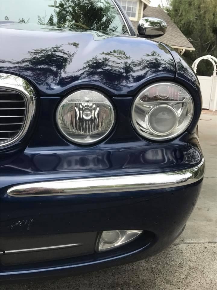 A blue car is parked in a driveway in front of a house.