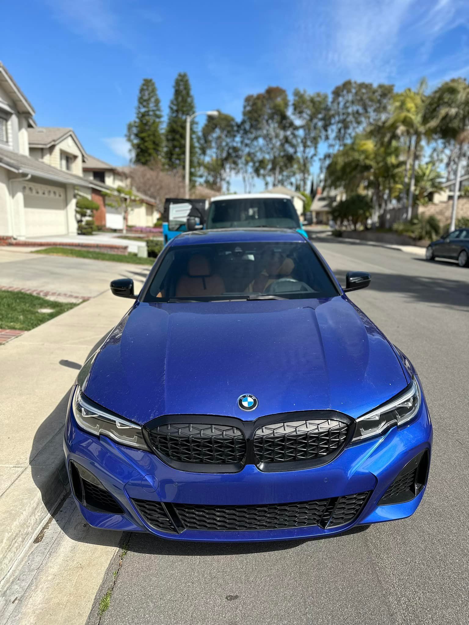 A blue bmw 3 series is parked on the side of the road.