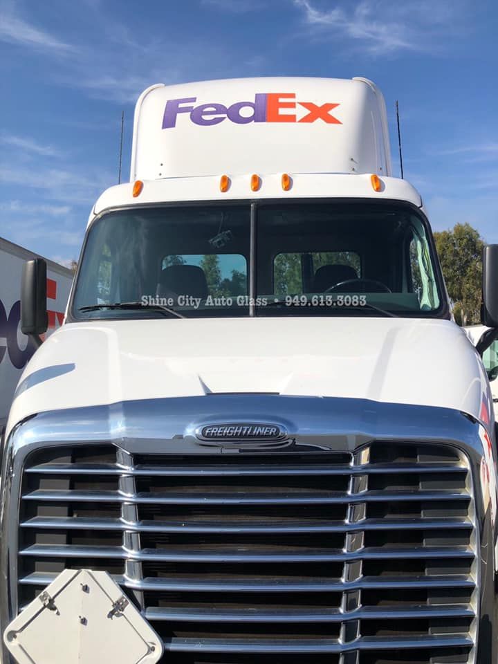 A white fedex truck is parked in a parking lot.
