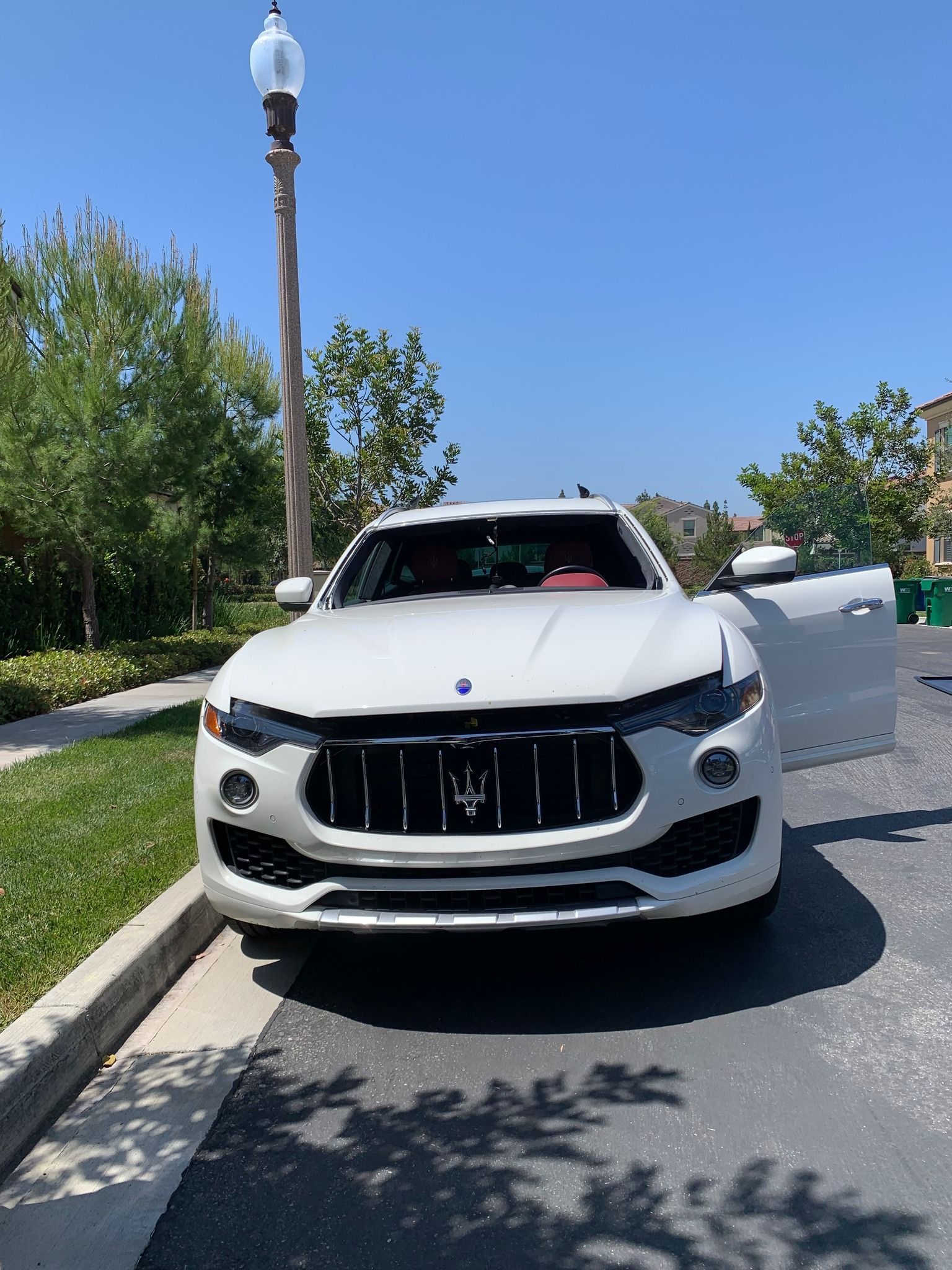 A white maserati is parked on the side of the road.