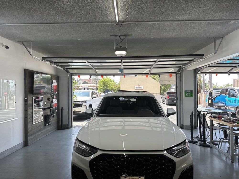 A white car is parked in a garage with the garage door open.