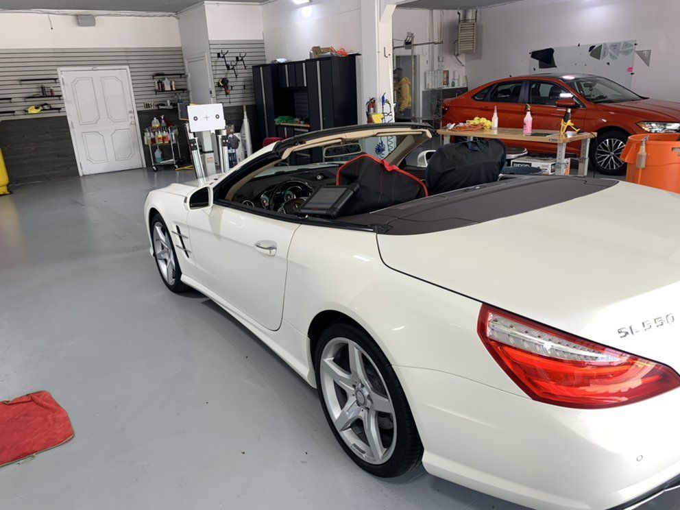 A white convertible car is parked in a garage.