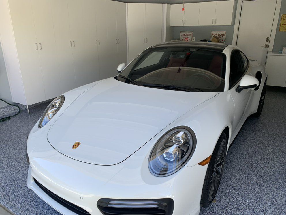 A white porsche 911 turbo is parked in a garage.