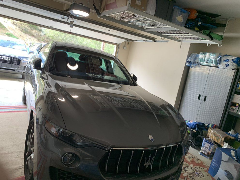 A gray maserati is parked in a garage.