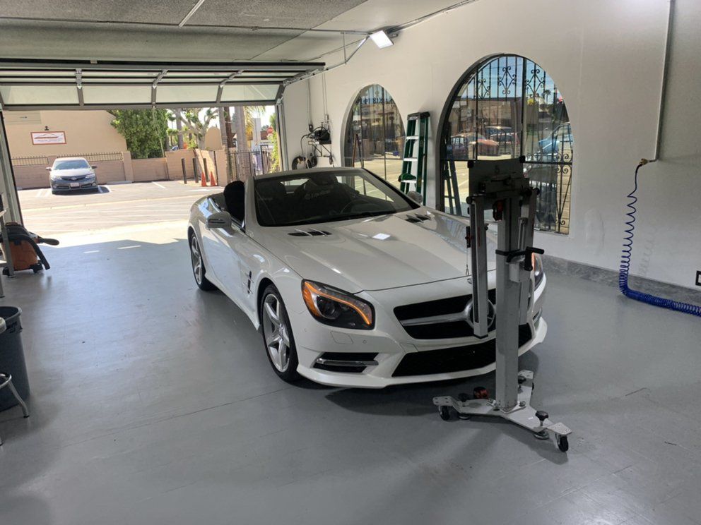 A white sports car is parked in a garage.
