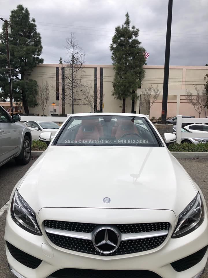 A white mercedes convertible is parked in a parking lot.
