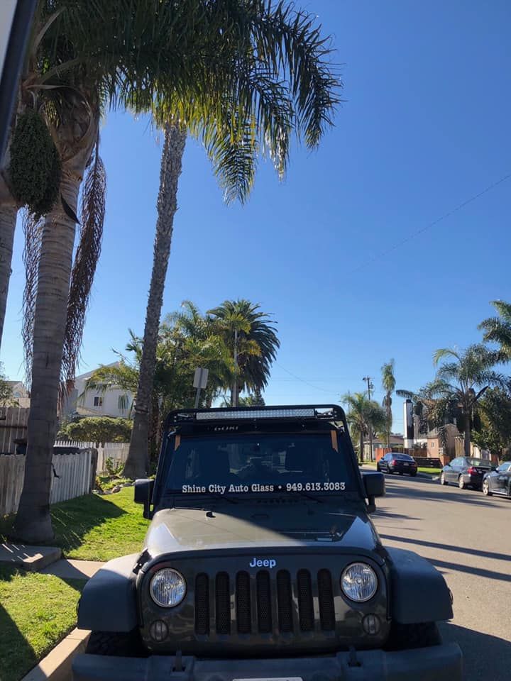 A jeep is parked on the side of the road next to palm trees