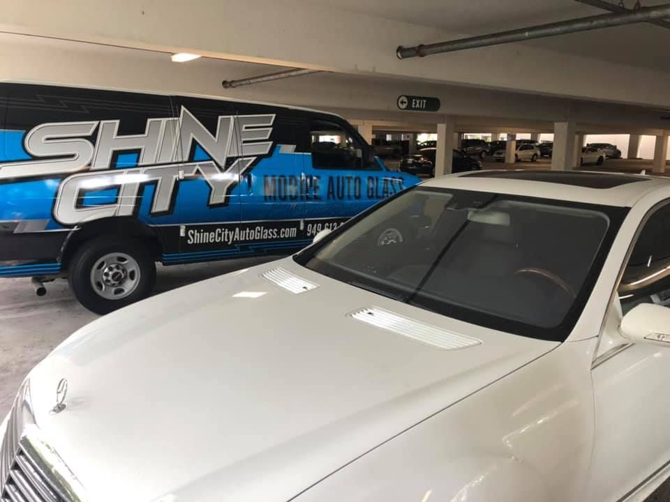 A white car is parked next to a blue van in a parking garage.