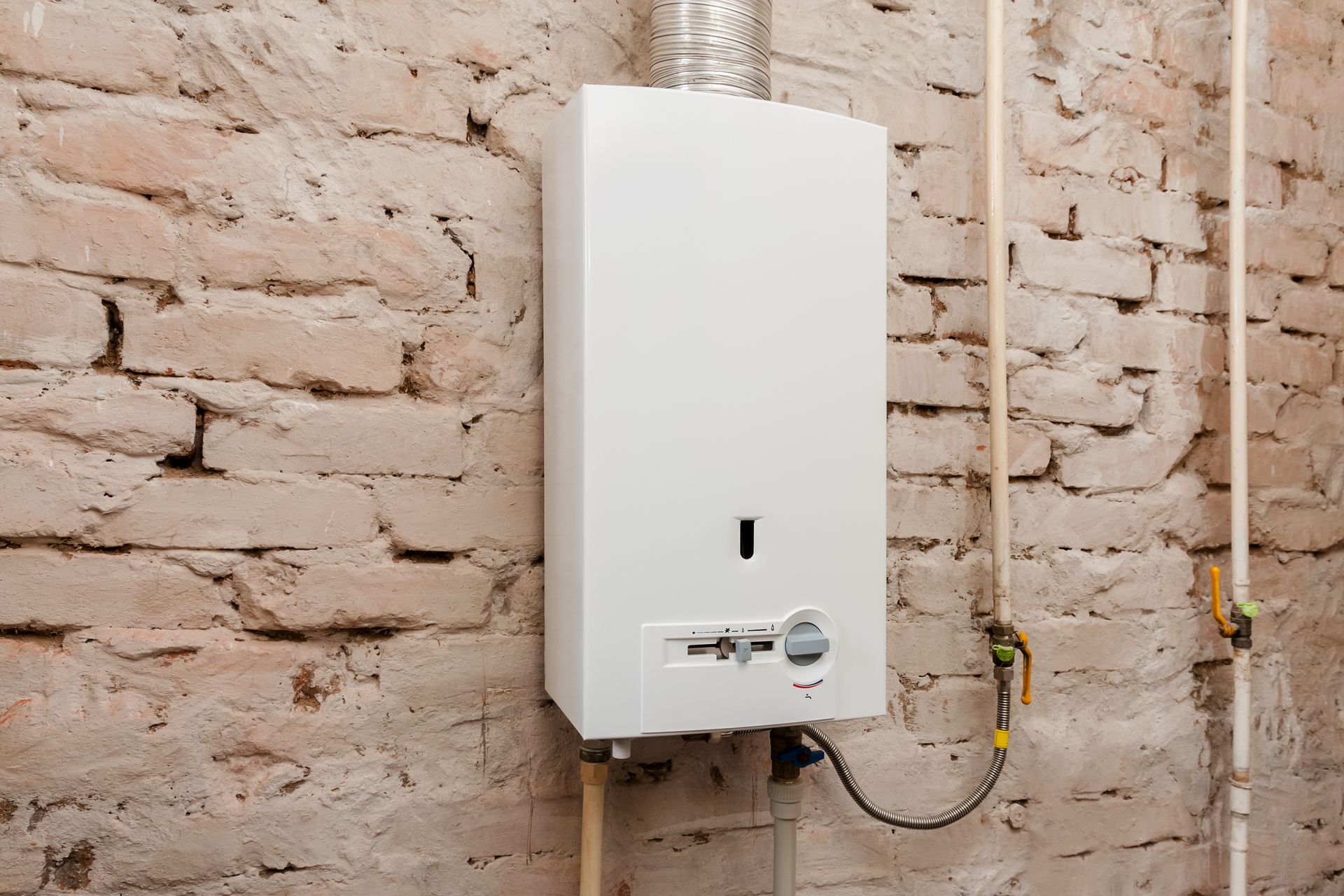 A white water heater is hanging on a brick wall.