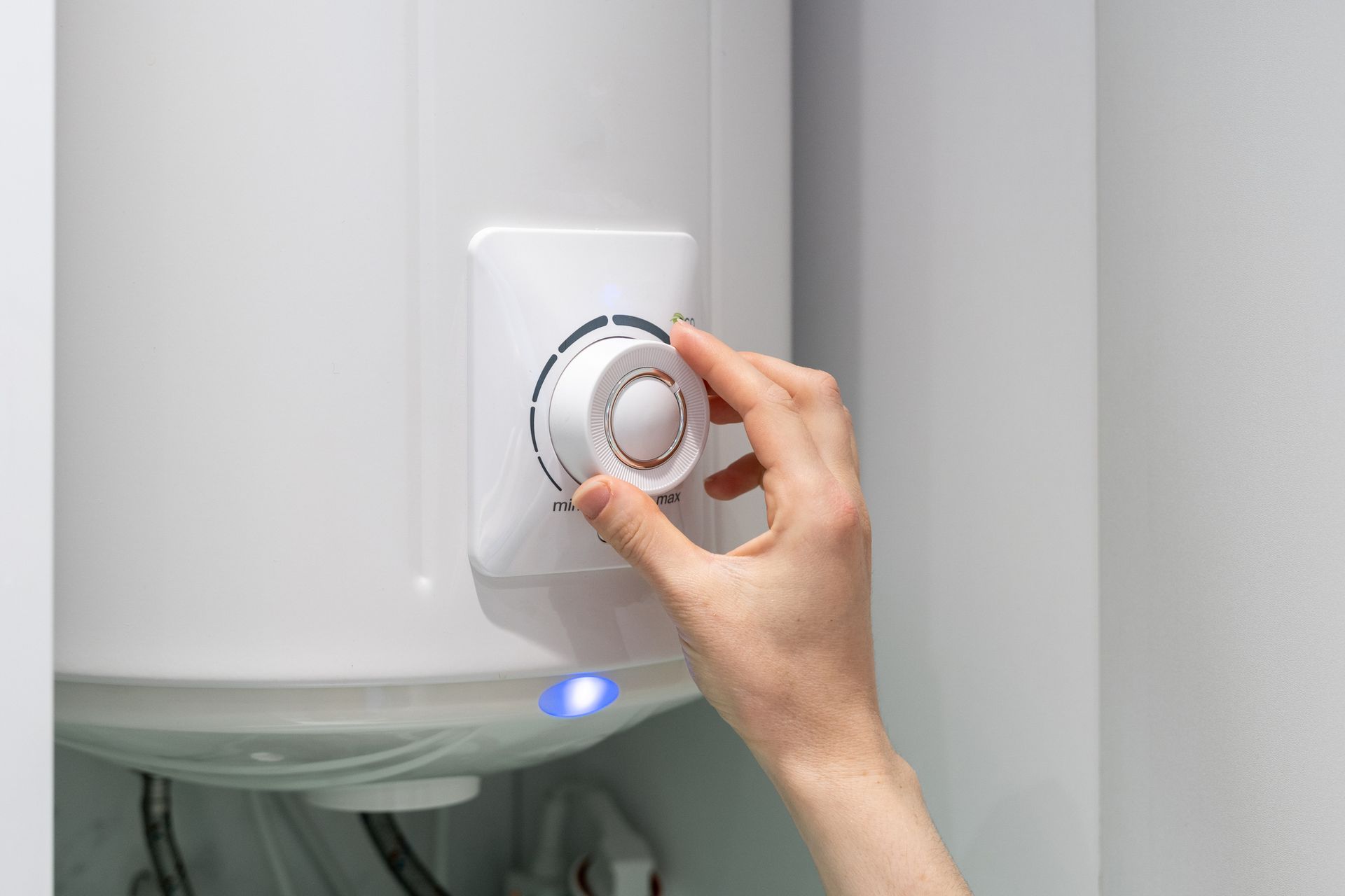 A person is adjusting the temperature of a water heater.