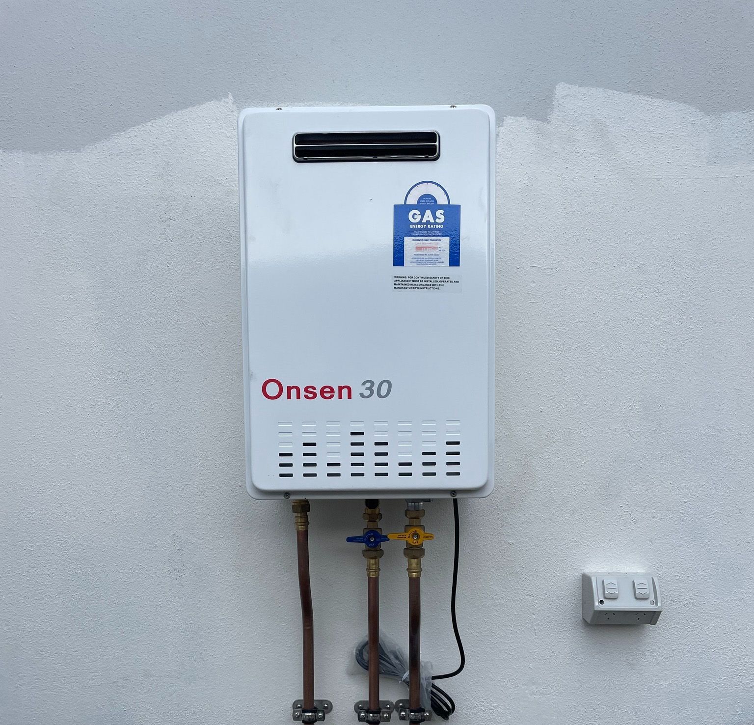 A white onsen 30 gas water heater mounted on a wall
