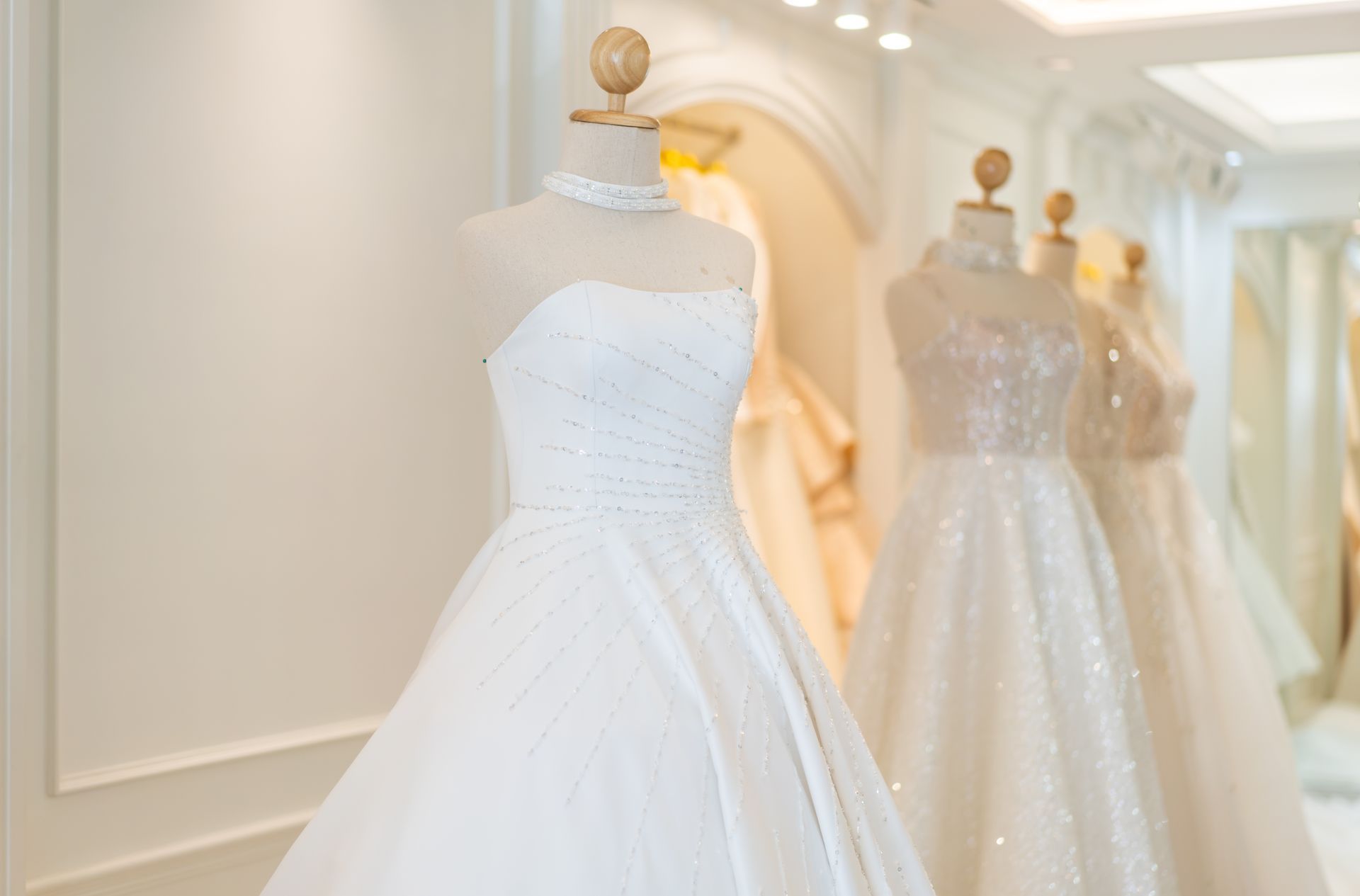 Wedding dresses displayed on mannequins in a bridal shop.