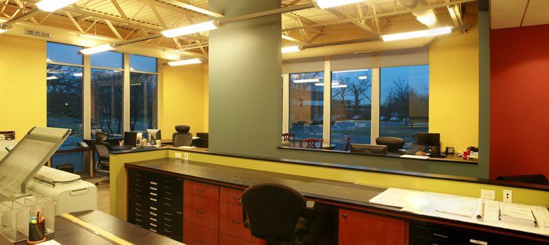 A room with a lot of windows and a desk with a printer on it