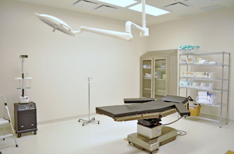 An empty operating room with an operating table and a light hanging from the ceiling.