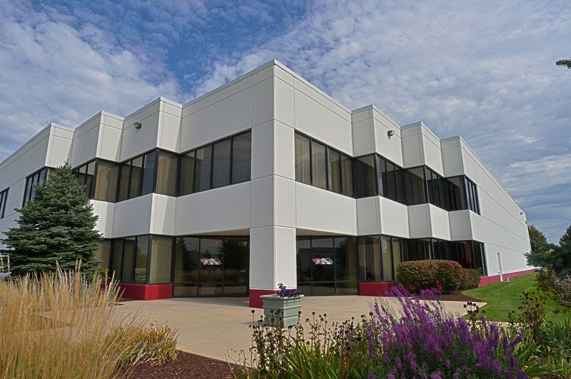 A large white building with purple flowers in front of it.