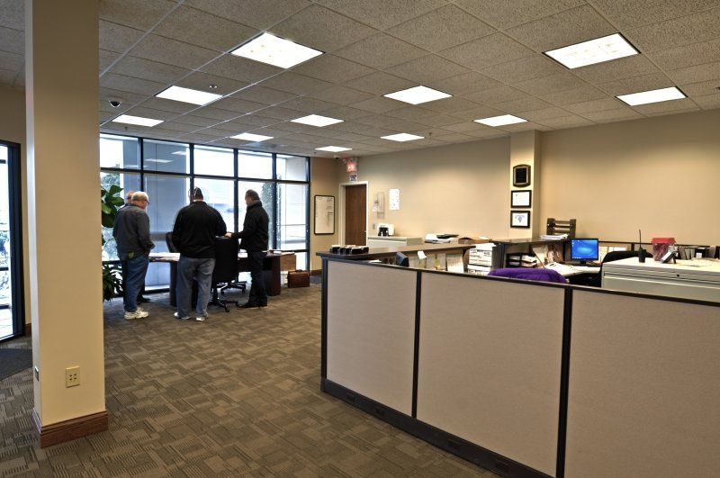 A group of people are standing around a counter in an office.