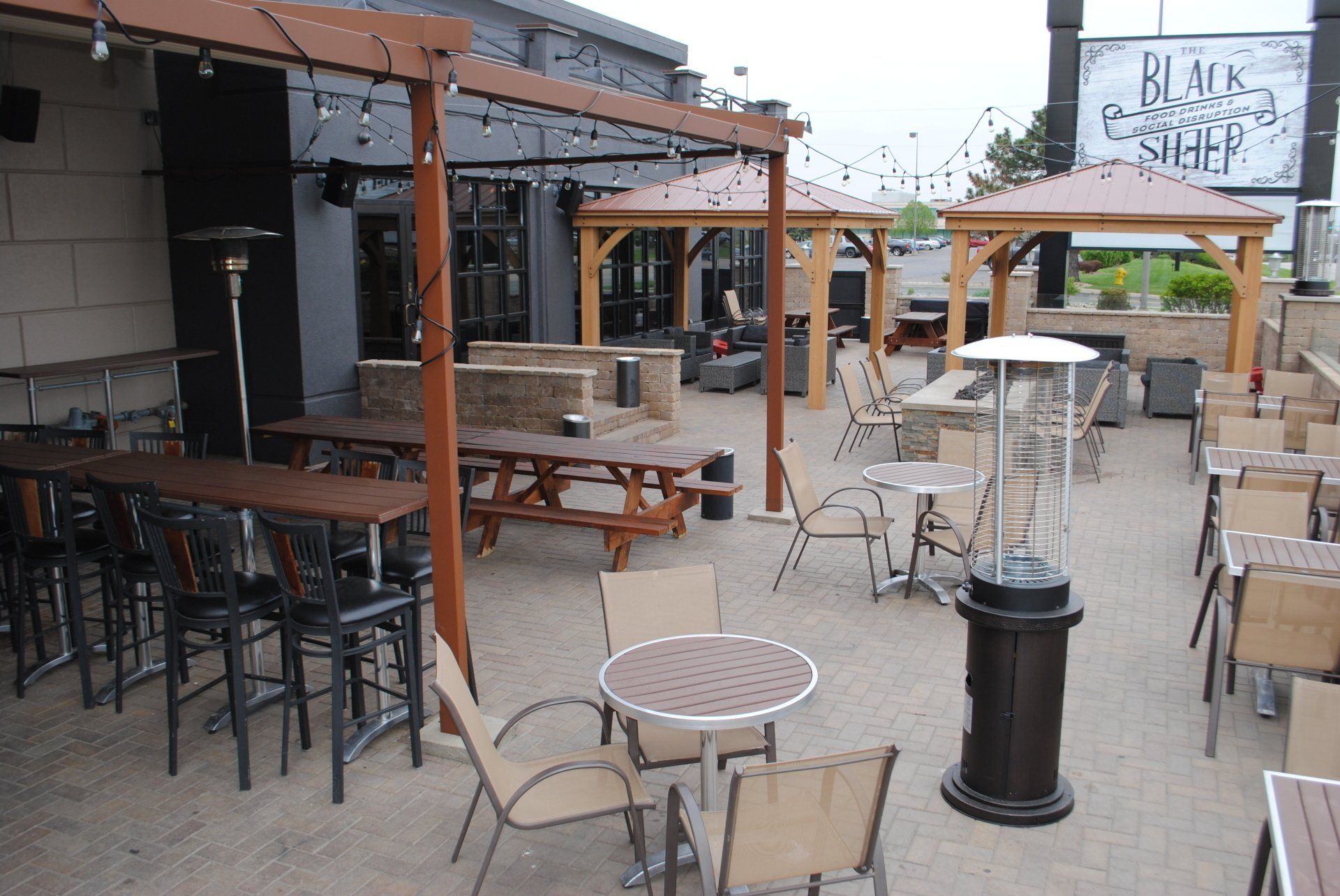 A patio with tables and chairs and a sign that says black sheep