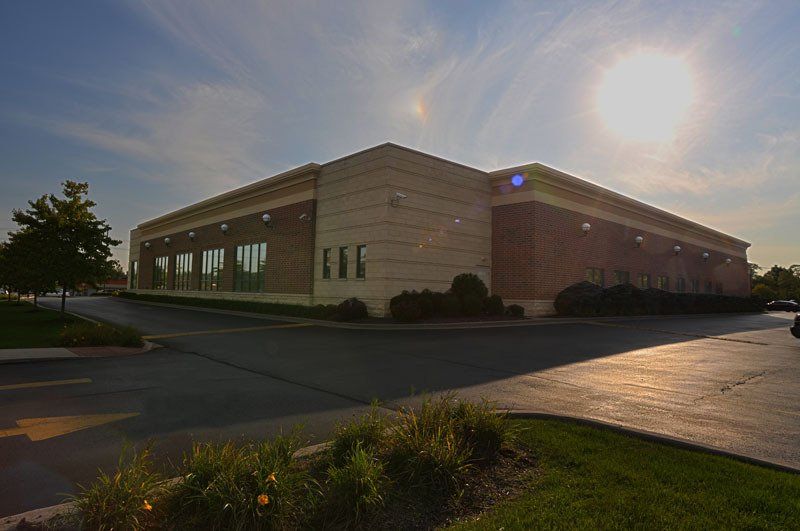 A large building with a lot of windows and a parking lot in front of it.