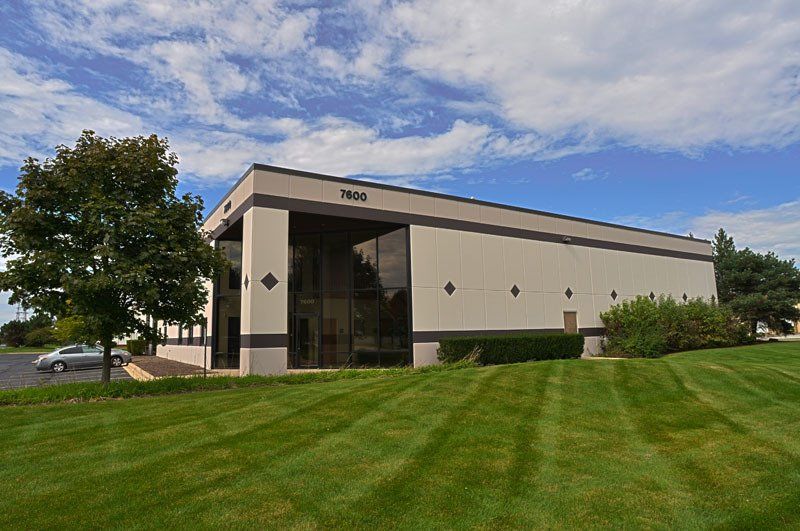 A large building with a lot of windows is sitting on top of a lush green field.