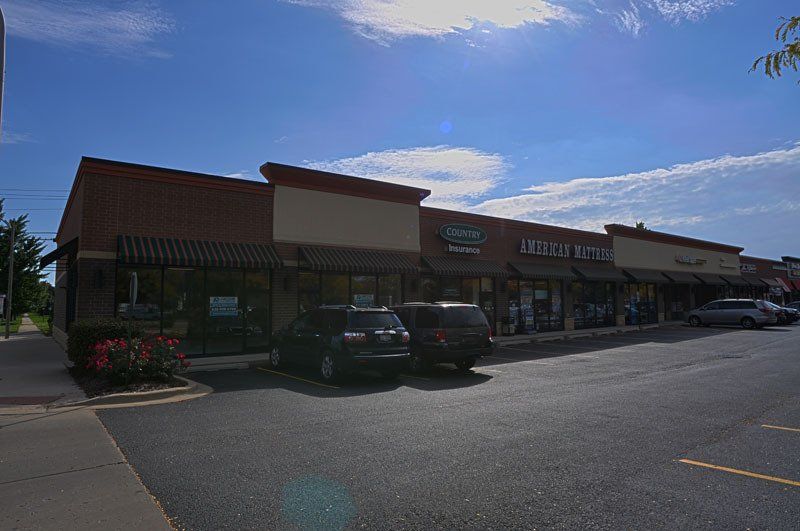 A row of buildings with cars parked in front of them on a sunny day.