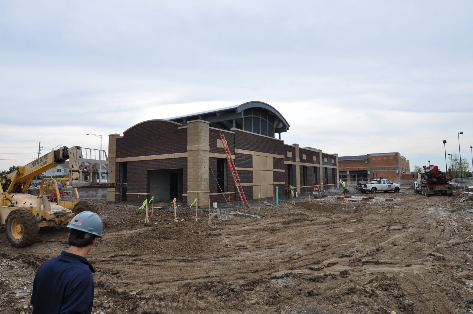 A man wearing a hard hat stands in front of a construction site