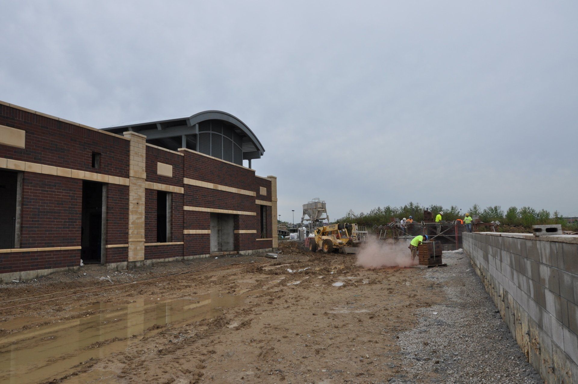 A construction site with a brick building in the background and a bulldozer in the foreground.
