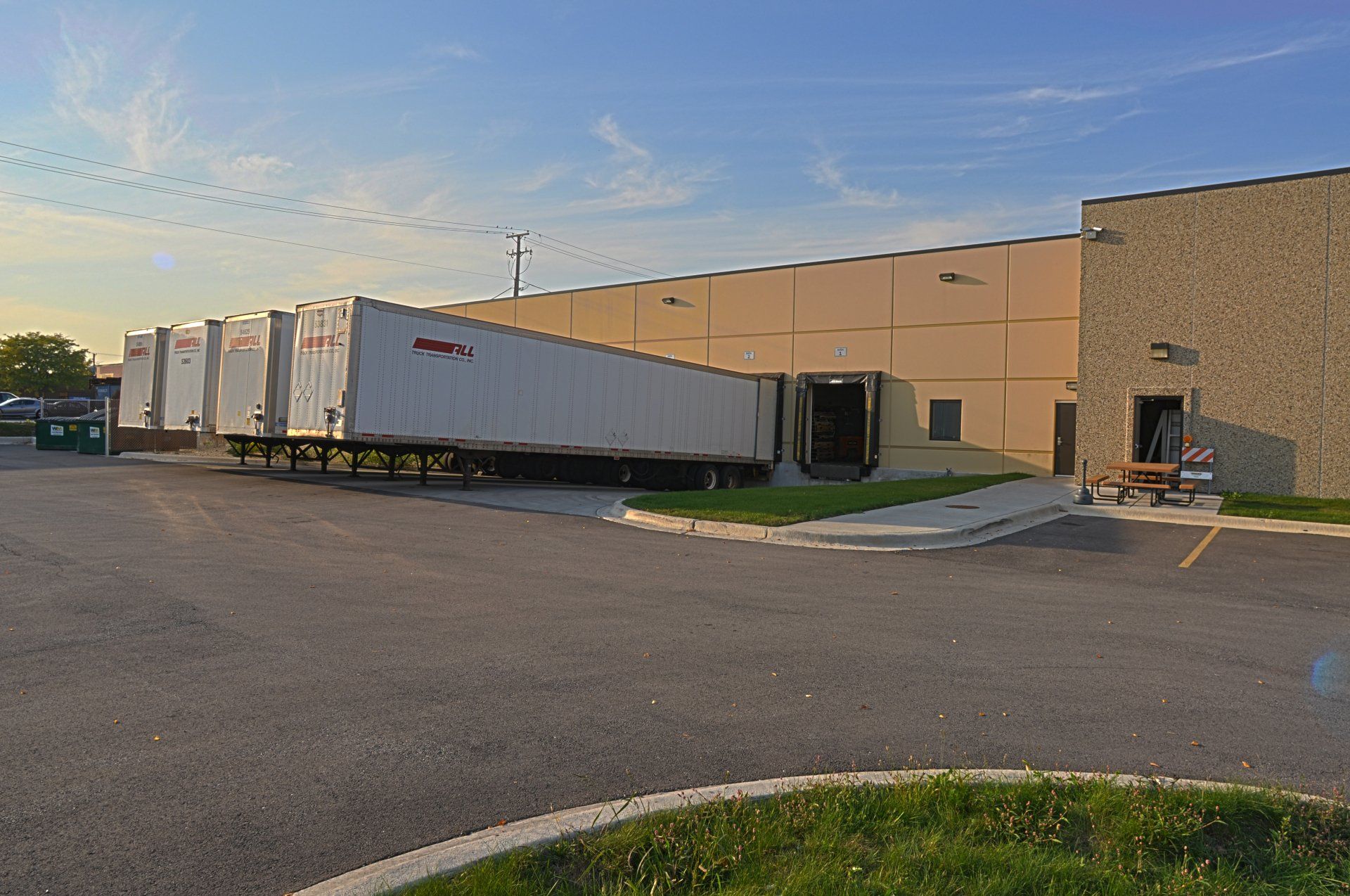A row of semi trucks are parked in front of a large building.